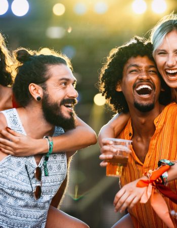 Group of happy young friends hanging out and enjoying drinks, festival